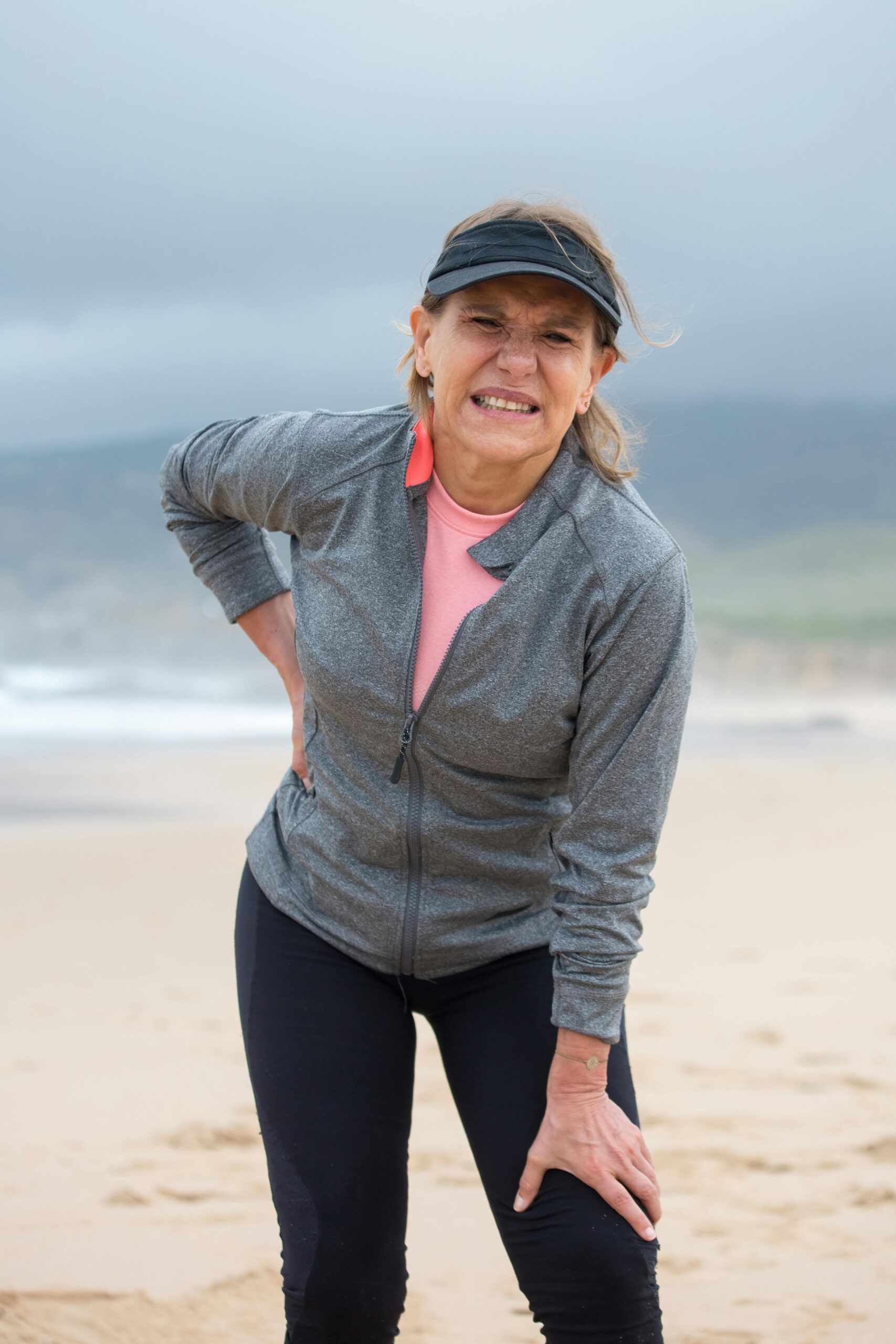Senior woman stretching on a sandy Portuguese beach, embracing an active lifestyle.